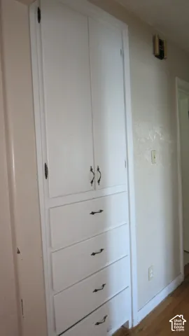 Built-in storage cabinet featuring white painted cabinetry, four stacked drawers, and dual-door cupboard space with metallic hardware