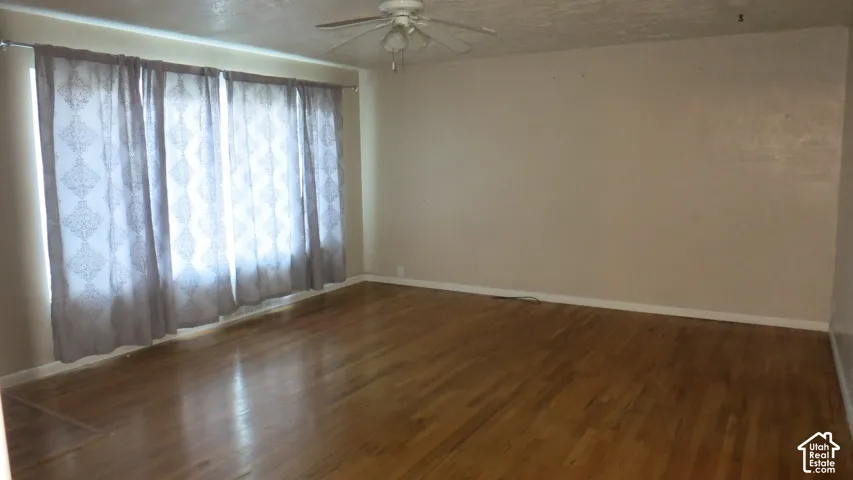 Room featuring wood-finish flooring, a ceiling fan with integrated lighting, and a large multi-panel window