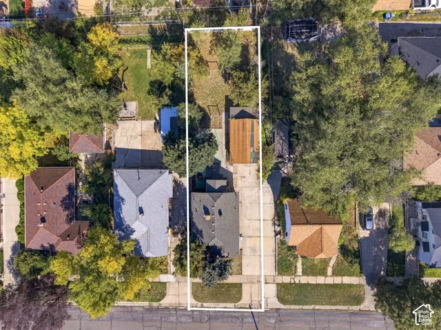 Aerial perspective of a rectangular lot featuring a detached garage, a concrete driveway, and mature landscaping