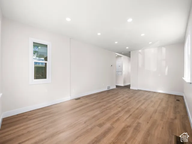 Neutral interior space featuring wood-finish flooring, recessed lighting, and crisp white wall paint