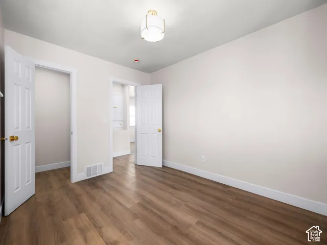 Neutral interior featuring wood-finish flooring, six-panel solid core doors, and a contemporary drum-style ceiling light fixture