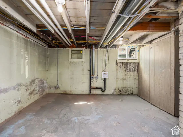 Unfinished basement area featuring concrete block walls, concrete flooring, exposed ceiling joists, and dual windows