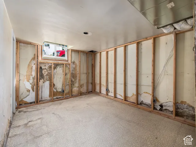 Unfinished interior space featuring exposed wood wall framing, resilient sheet flooring, and a single-pane vinyl-frame window