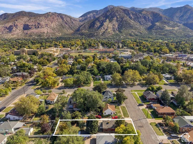 Aerial perspective featuring a residential lot with mature trees and a prominent mountain backdrop