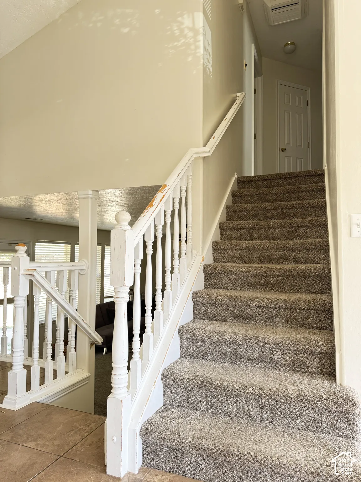 Staircase featuring carpeted steps, a white wooden balustrade, and a prominent newel post