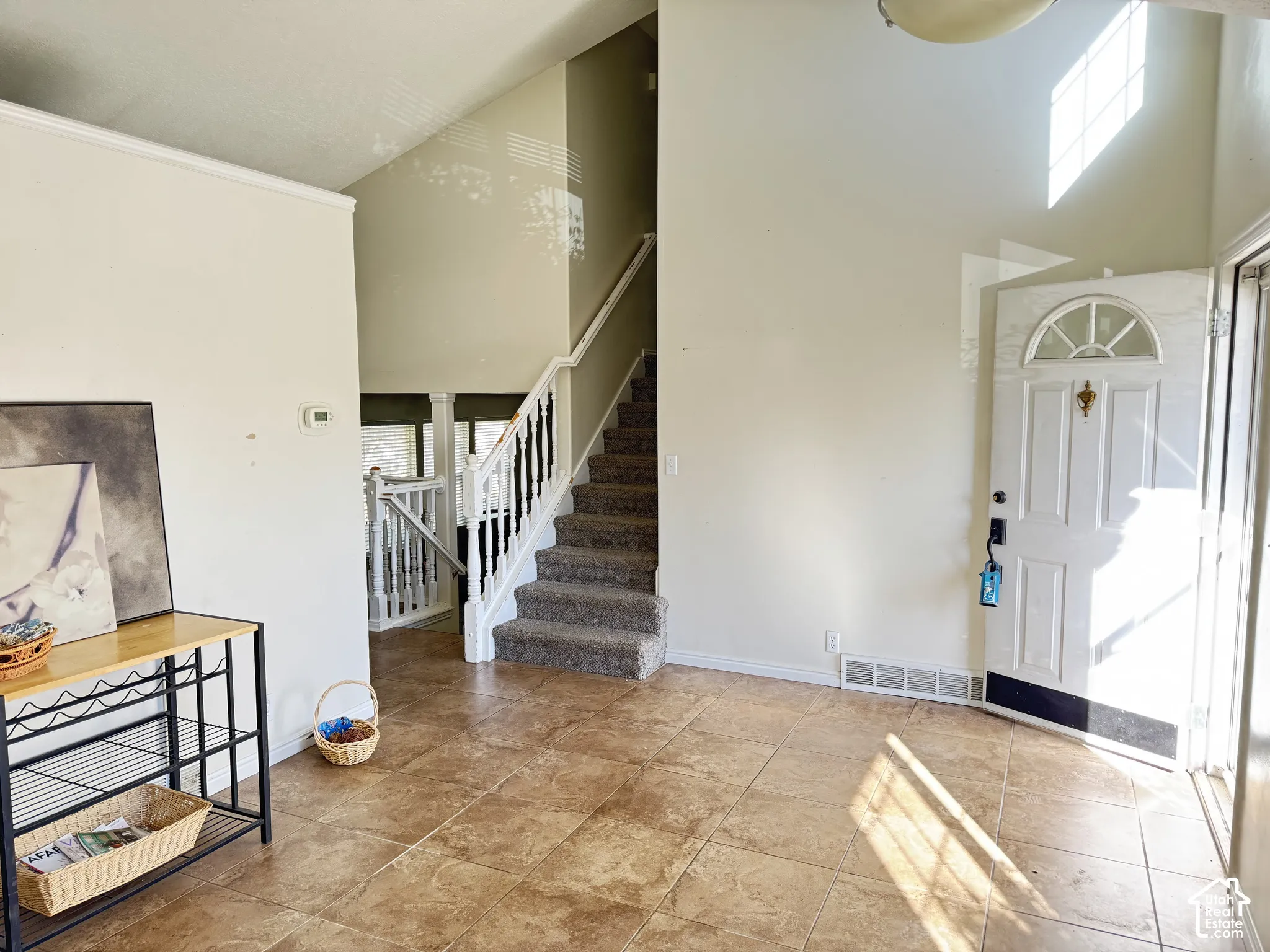 Entryway featuring high vaulted ceilings, tile flooring, and a staircase with a white railing