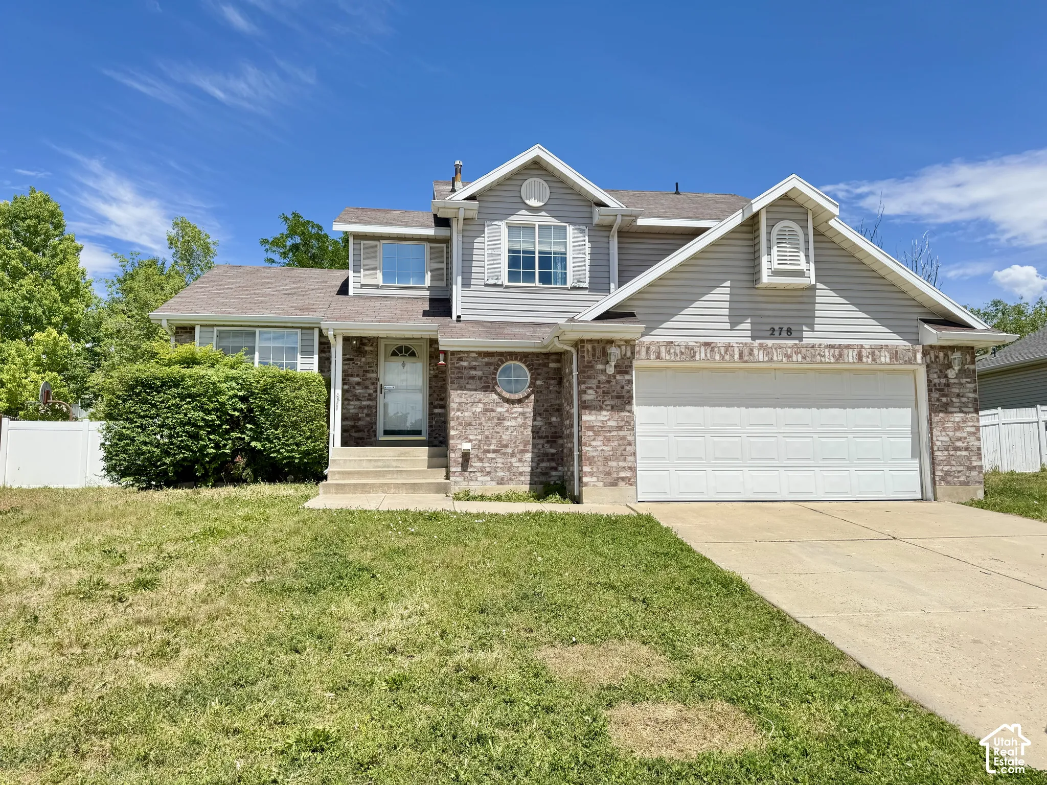 Two-story residence featuring a mixed brick and horizontal siding exterior, dual-gabled roofline, front-facing two-car garage, and a concrete driveway