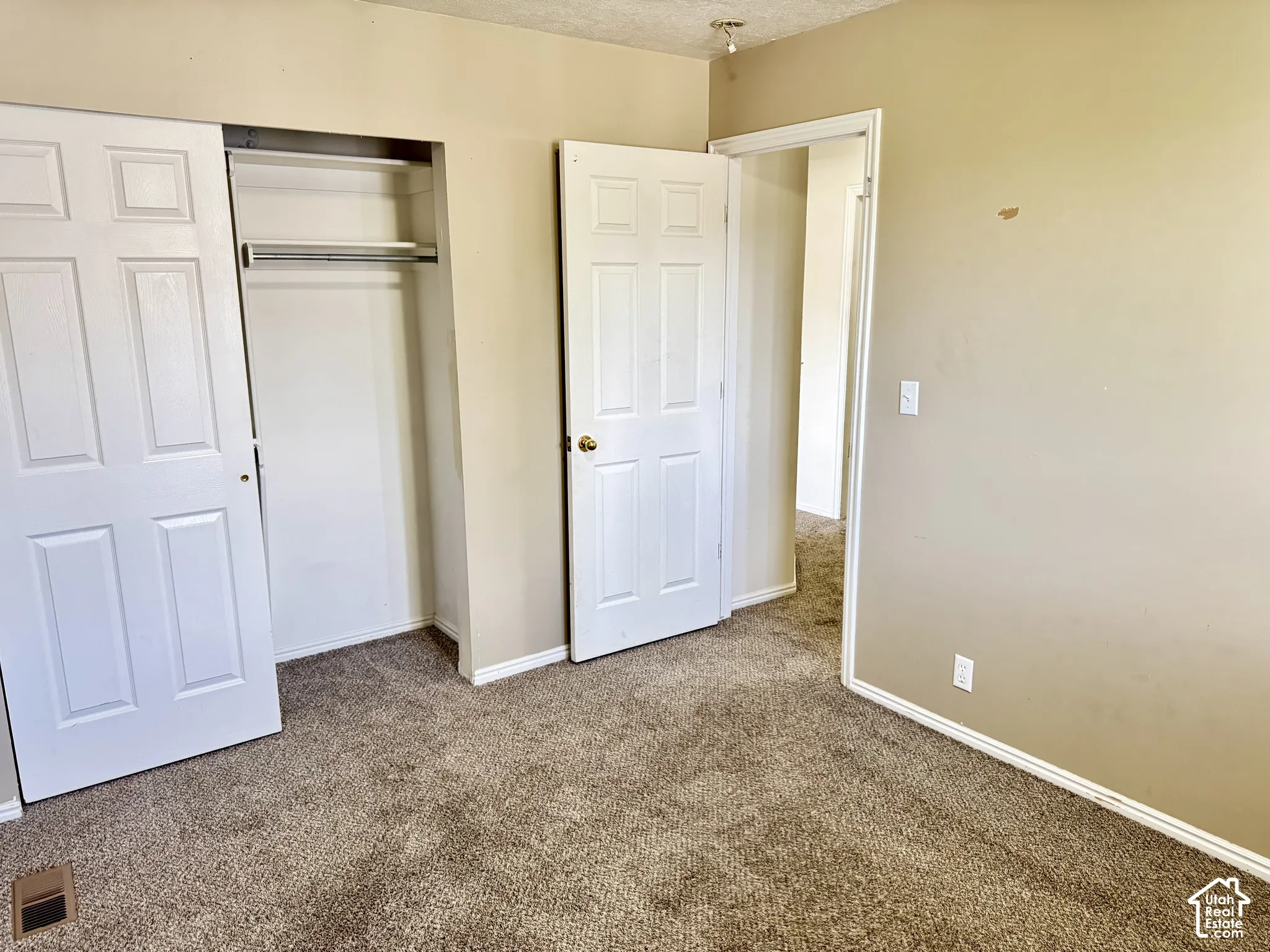 Interior space featuring neutral-toned walls, carpeting, dual-panel interior doors, and a built-in closet with overhead shelving and a hanging rod