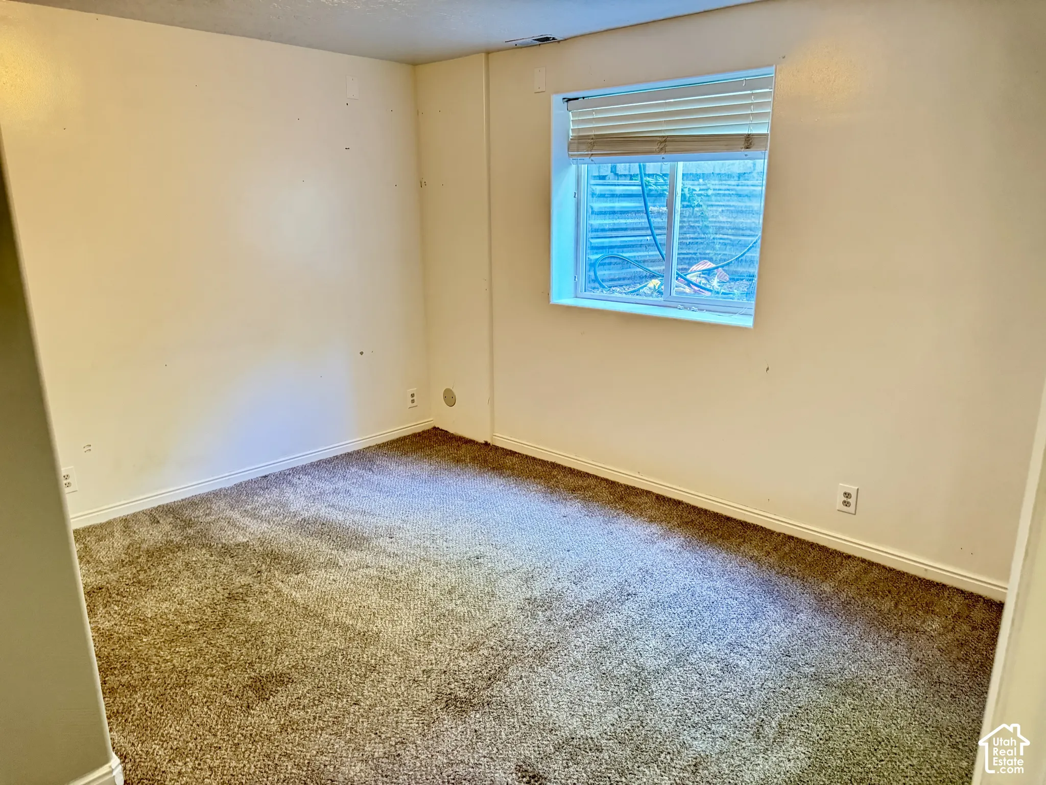 Carpeted room featuring neutral walls and a window with integrated blinds