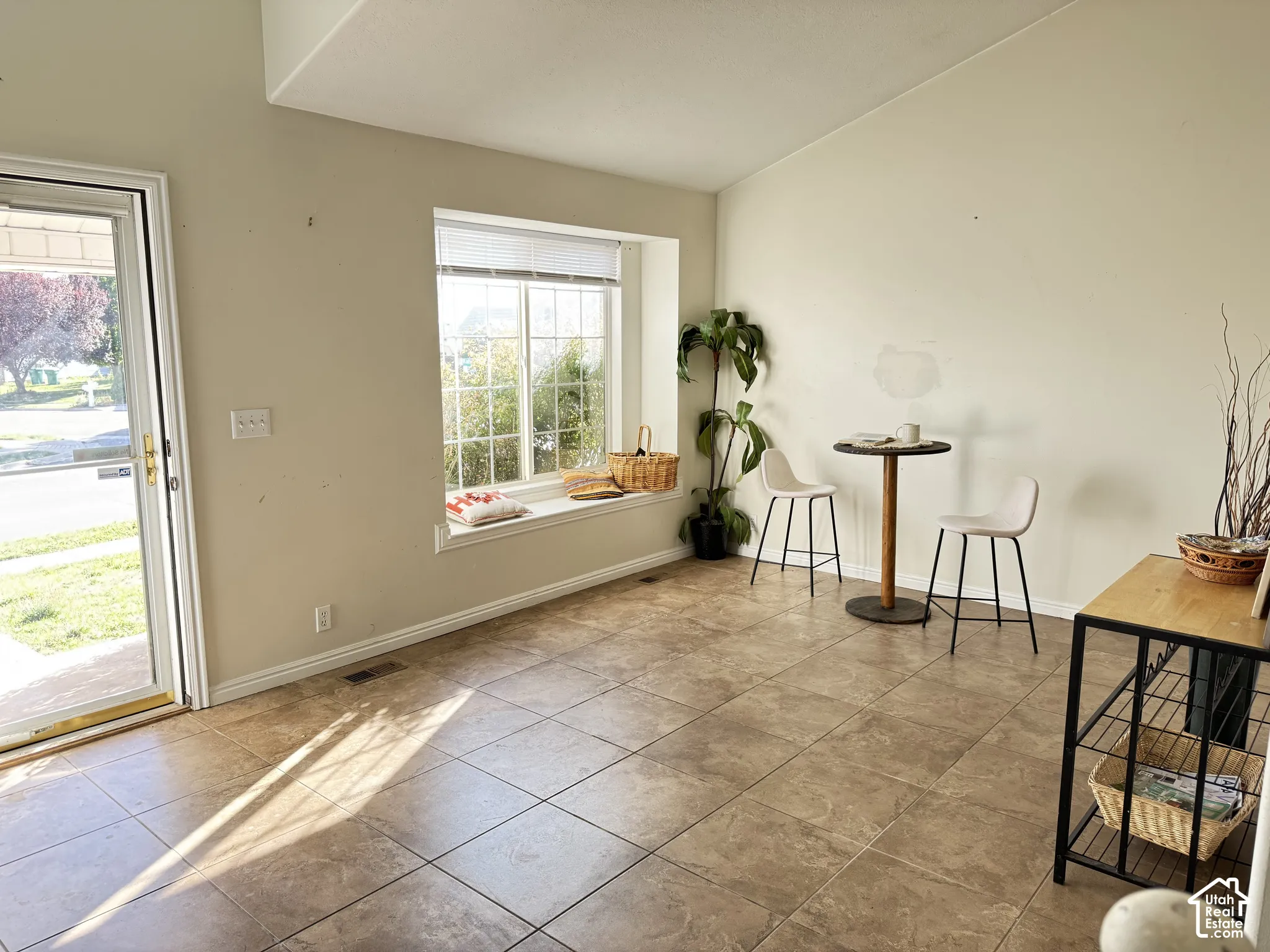 Tile flooring, vaulted ceiling, large bay window, and exterior glass door with grid detailing