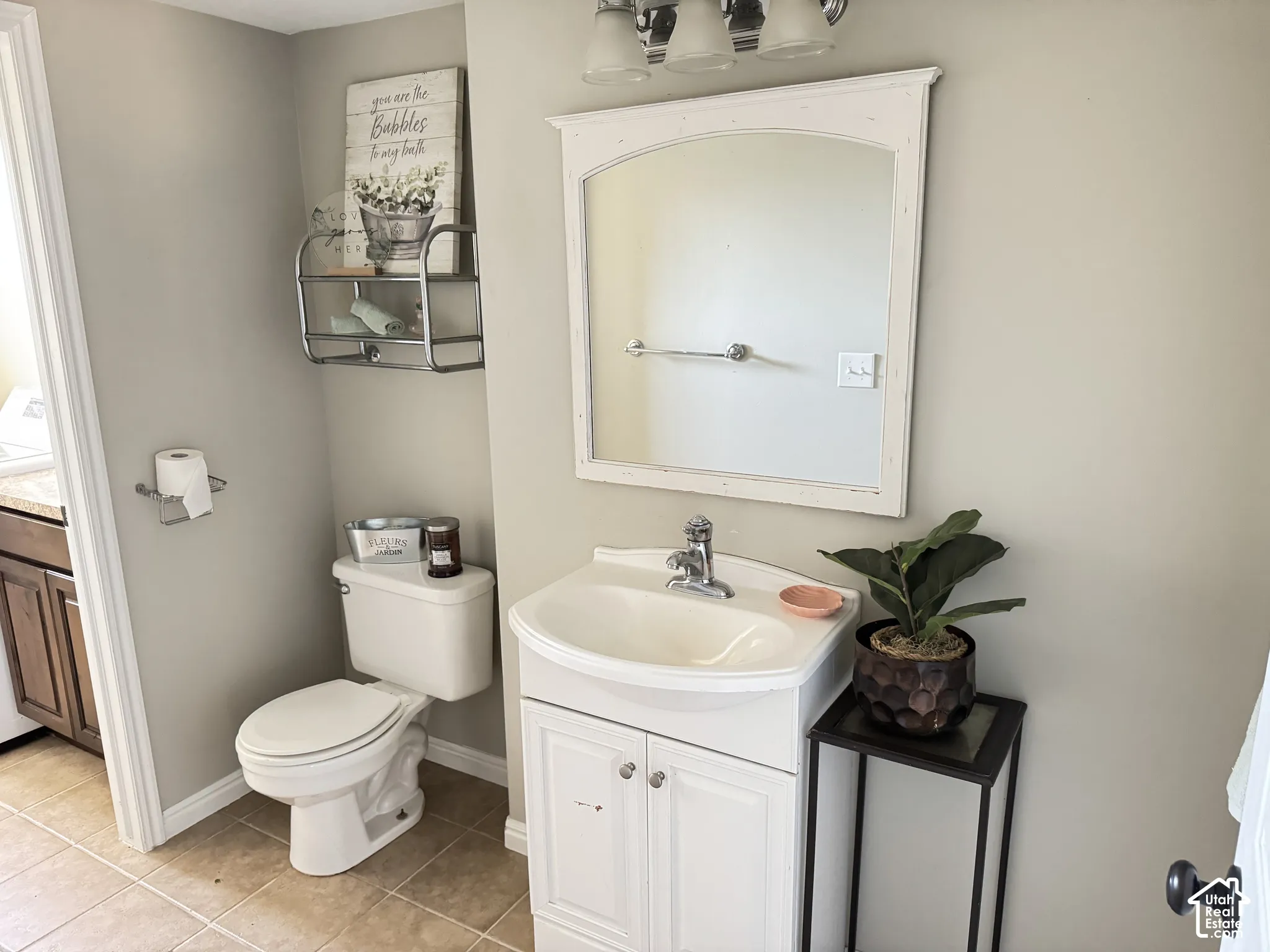 Bathroom featuring a white pedestal-style vanity with integrated sink, chrome faucet, arched framed mirror, and three-light wall-mounted fixture