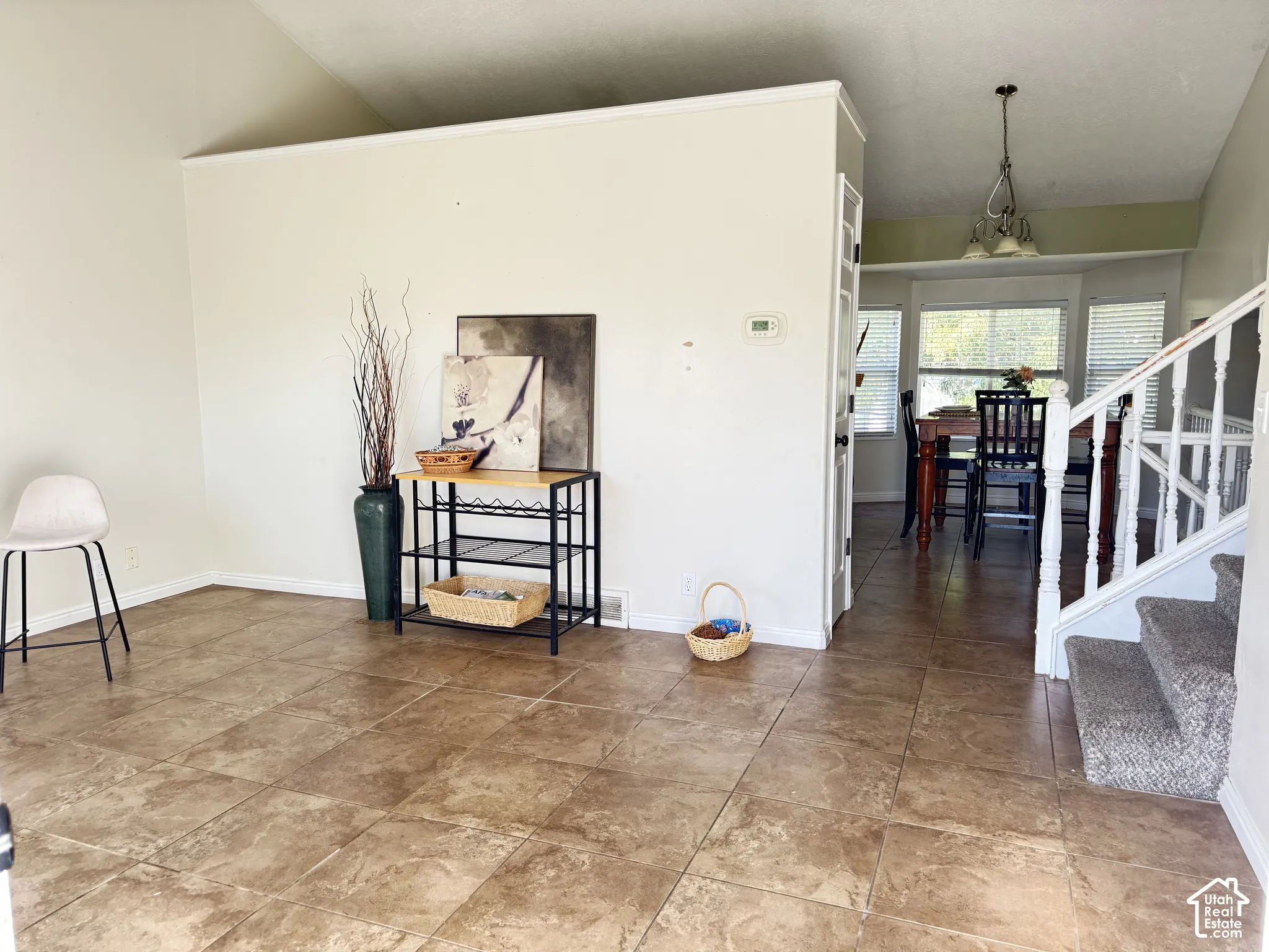 Open-concept interior featuring vaulted ceilings, tile flooring, a multi-paneled bay window, and a staircase with white painted balusters and railings
