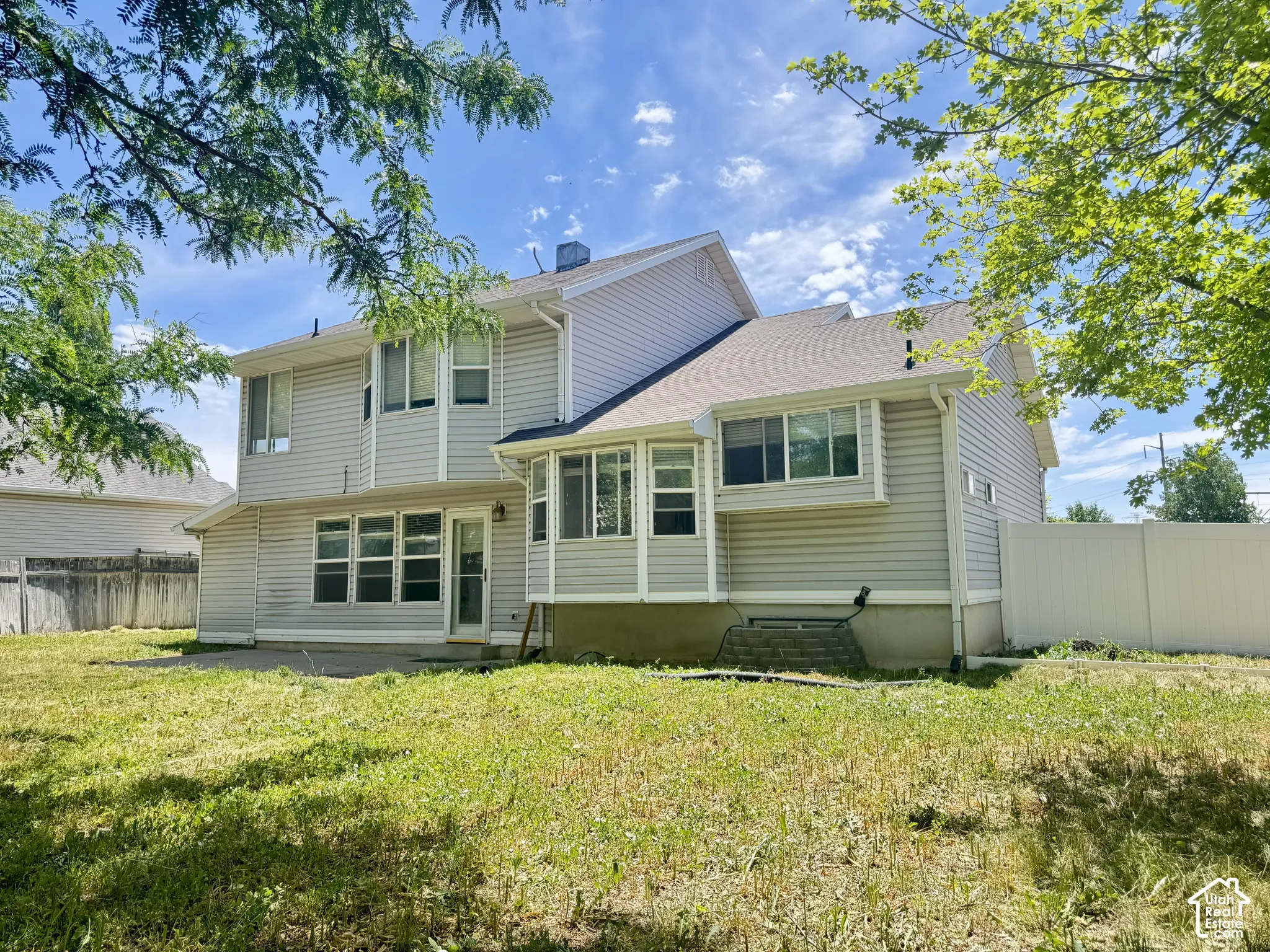 Rear exterior featuring horizontal lap siding, multi-level bay window architecture, and a concrete patio