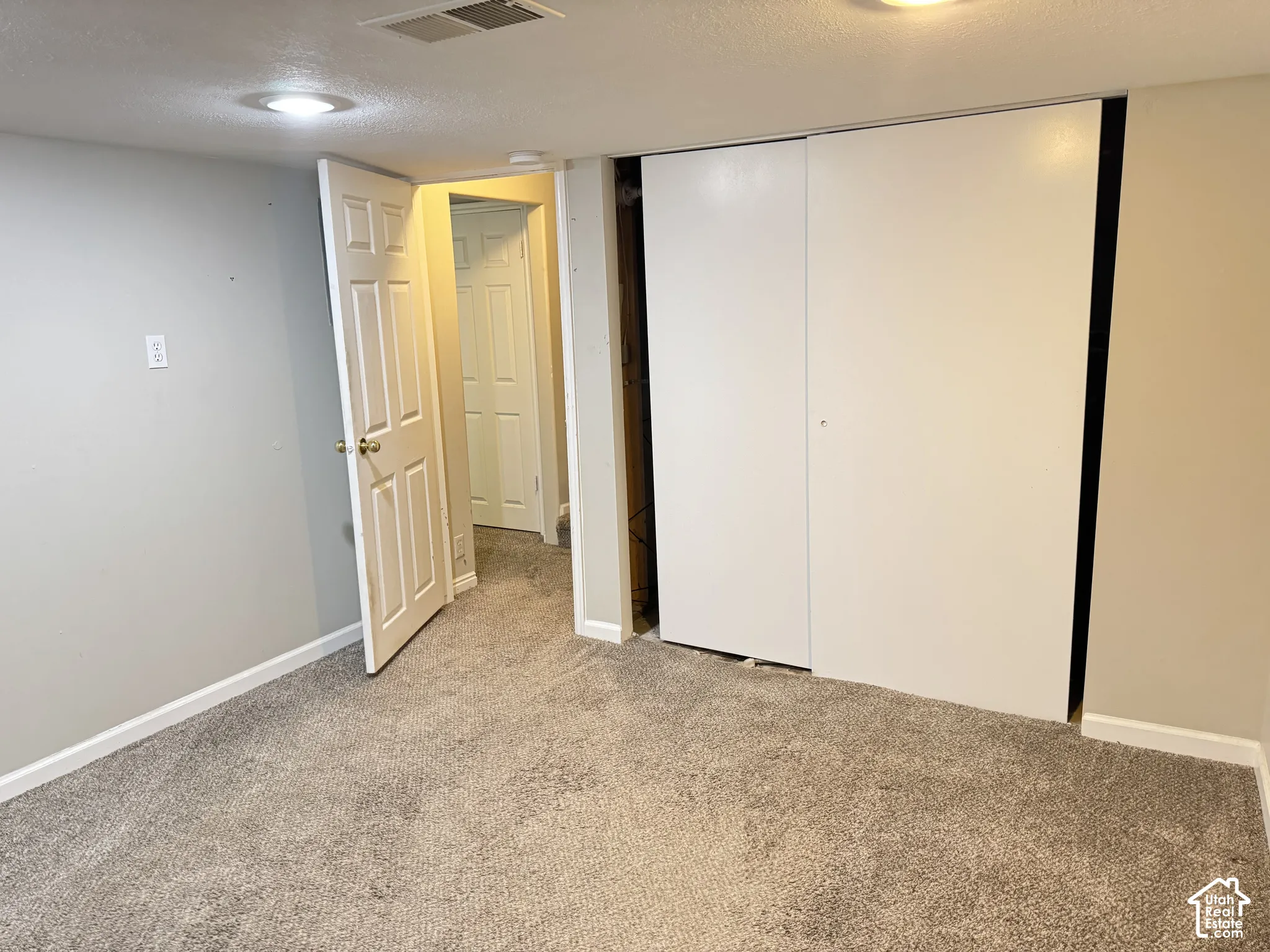 Neutral-toned room featuring wall-to-wall carpeting, recessed ceiling lighting, a closet with sliding doors, and six-panel interior doors