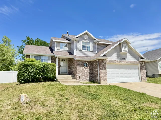 Multi-level exterior featuring a brick and horizontal siding facade, two-car garage, and decorative round window