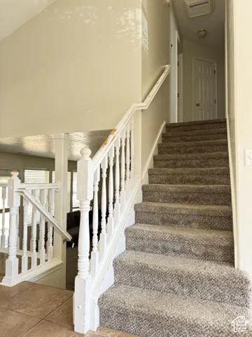 Staircase featuring carpeted steps, a white wooden balustrade, and a prominent newel post