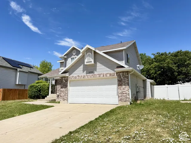 Two-story residence featuring grey horizontal siding, a stone veneer facade, an attached two-car garage, and a concrete driveway