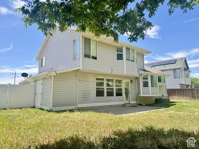 Two-story residence featuring light-colored horizontal siding, a concrete rear patio, and a white privacy fence