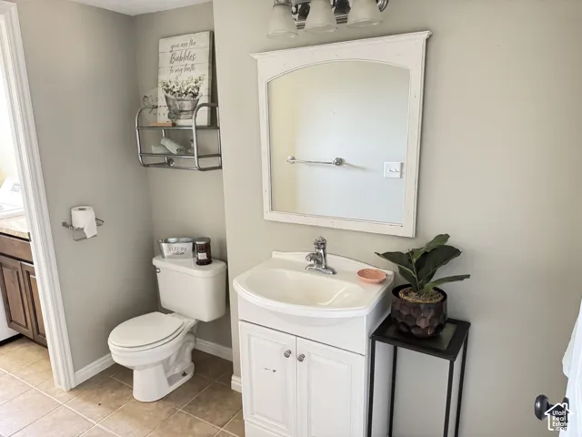 Bathroom featuring a white pedestal-style vanity with integrated sink, chrome faucet, arched framed mirror, and three-light wall-mounted fixture