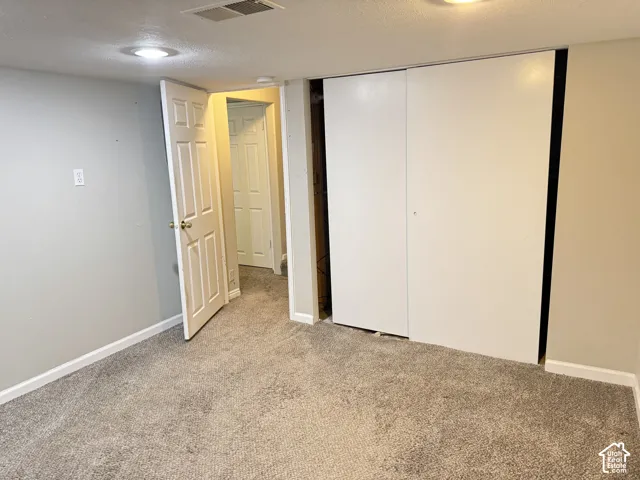 Neutral-toned room featuring wall-to-wall carpeting, recessed ceiling lighting, a closet with sliding doors, and six-panel interior doors