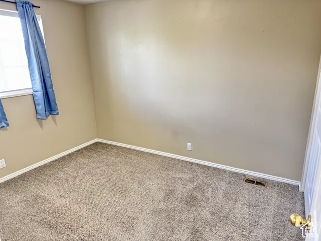 Neutral-toned interior room featuring wall-to-wall carpeting and a single-pane window
