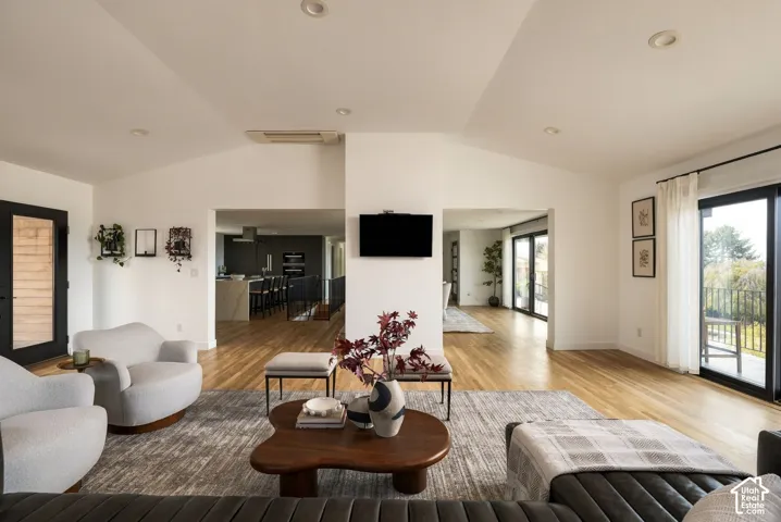 Vaulted ceilings with recessed lighting, wood-finish flooring, and expansive sliding glass doors providing outdoor access