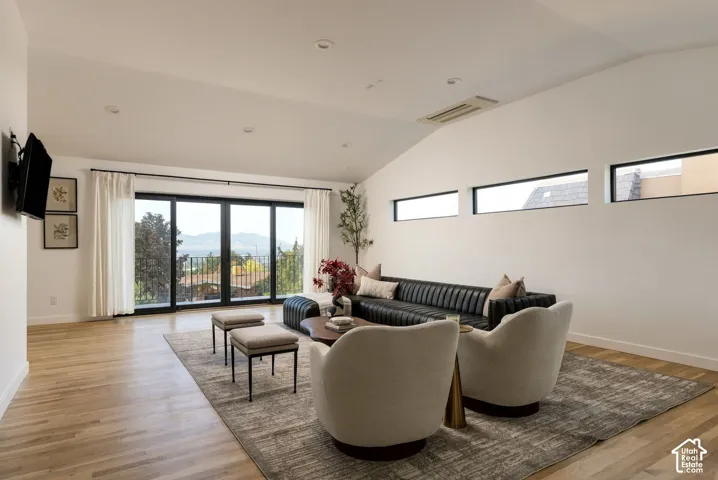 Vaulted ceilings, wood-finish flooring, recessed lighting, expansive multi-panel sliding glass doors, and clerestory windows