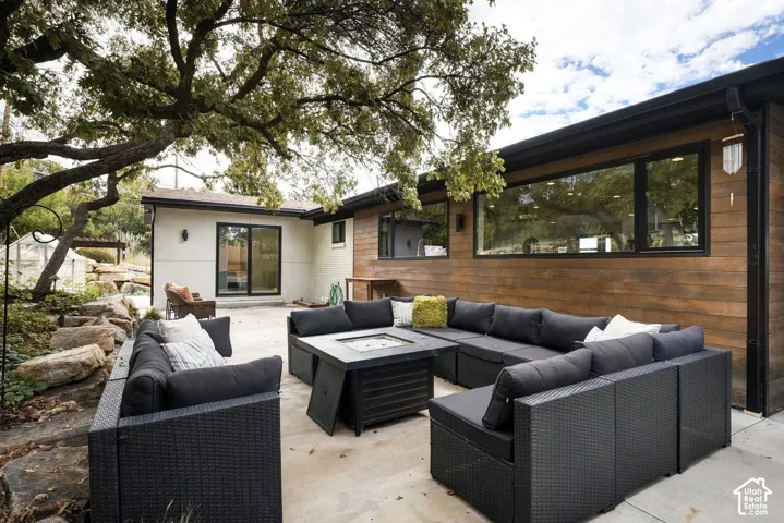 Concrete patio featuring horizontal wood-finish siding, large-format glass windows with black frames, and natural stone hardscaping