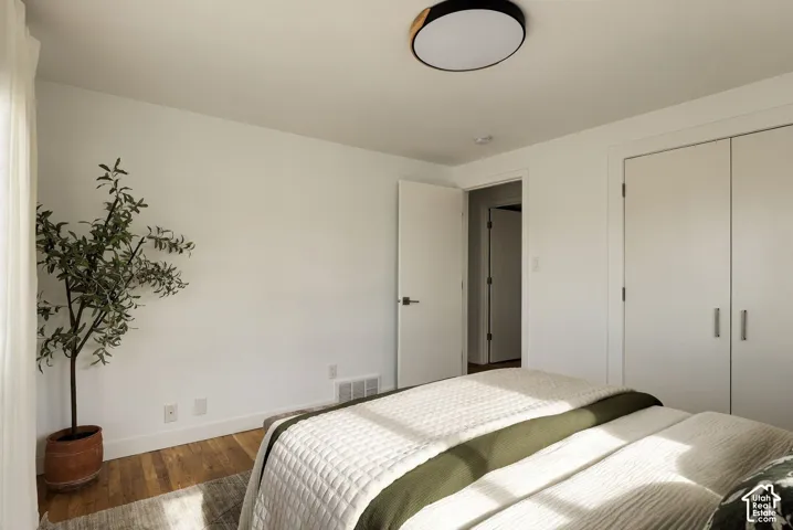 Bedroom interior featuring wood-finish flooring, white walls, double-door reach-in closet, and a circular flush-mount ceiling light fixture