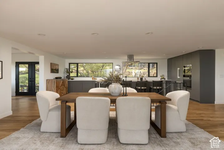 Open-concept kitchen featuring flat-panel cabinetry, built-in wall ovens, and recessed lighting, finished with wood-finish flooring and double-door exterior access