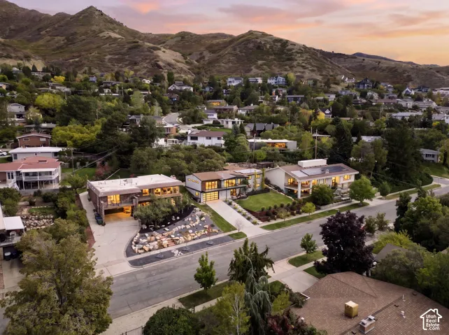 Aerial perspective showcasing multi-level residences with terraced hardscaping, manicured lawns, stone-accented landscaping, and mountain backdrop