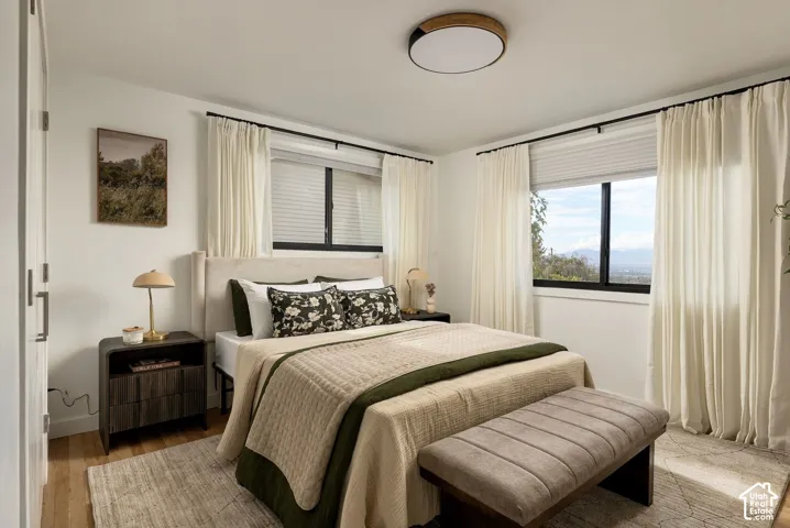 Neutral walls featuring large windows with black frames, wood-finish flooring, and a modern circular ceiling light fixture