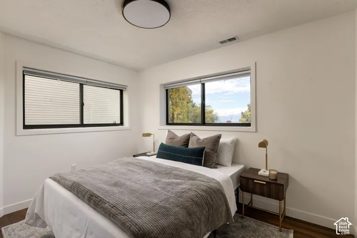 Dual-aspect windows with black frames, wood-finish flooring, and minimalist ceiling-mounted lighting
