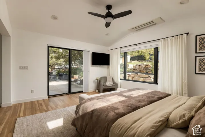 Vaulted ceilings featuring a black matte ceiling fan, wood-finish flooring, sliding glass door, and large windows with black frames