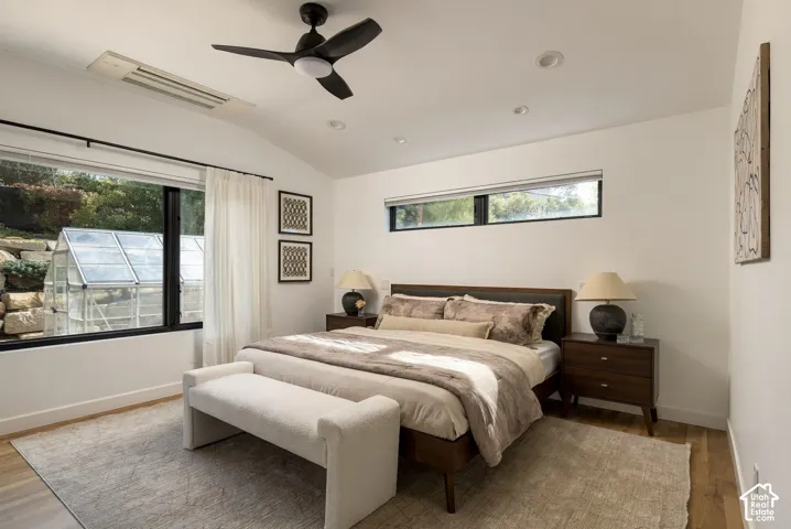 Vaulted ceiling featuring a matte black ceiling fan, wood-finish flooring, recessed lighting, and expansive black-framed windows