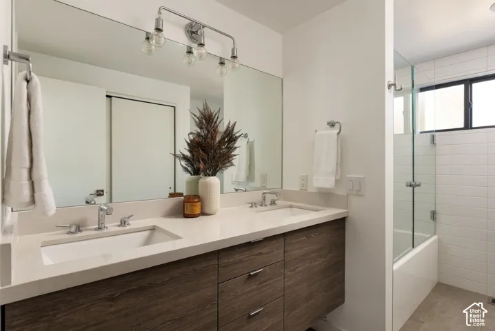 Double vanity featuring wood-finish cabinetry, quartz countertops, undermount rectangular sinks, chrome widespread faucets, and a full-width mirror