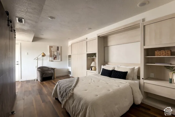 Custom light-toned built-in cabinetry with integrated shelving and recessed ceiling lighting, complemented by wide-plank wood-finish flooring and a dark-finished sliding door system