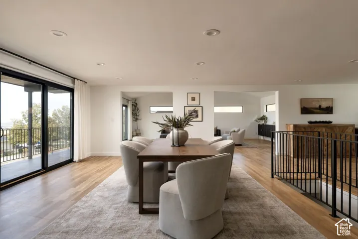 Open-concept living space featuring wood-finish flooring, recessed lighting, sliding glass doors, and a black metal railing