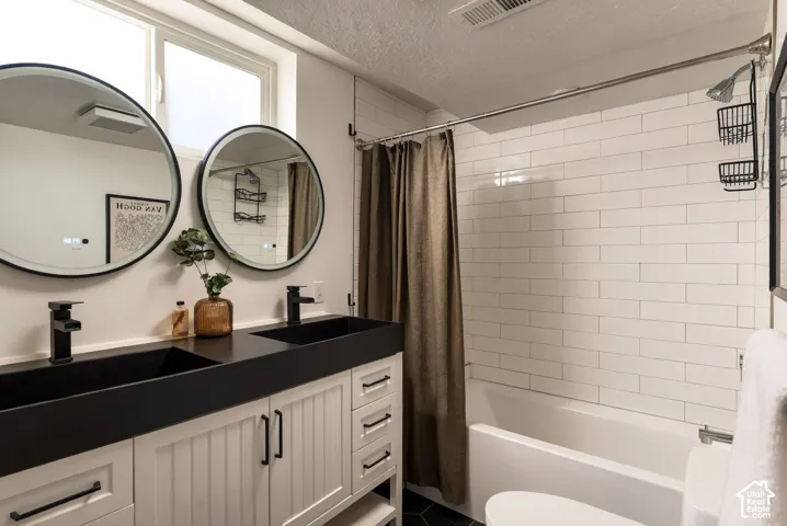 Double vanity featuring matte black rectangular integrated sinks, white beadboard cabinetry, dual circular backlit mirrors, and a tub-shower combination with white subway tile surround