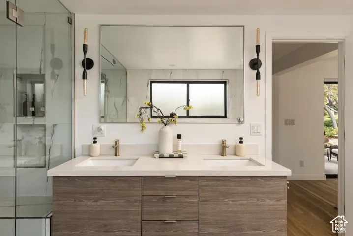 Dual-vanity cabinet with wood-finish cabinetry, quartz countertop, integrated rectangular sinks, metal-finish faucets, and wall-mounted light fixtures