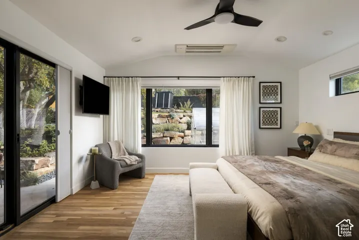 Vaulted ceiling with a matte black ceiling fan, wood-finish flooring, sliding glass door, and large black-framed windows