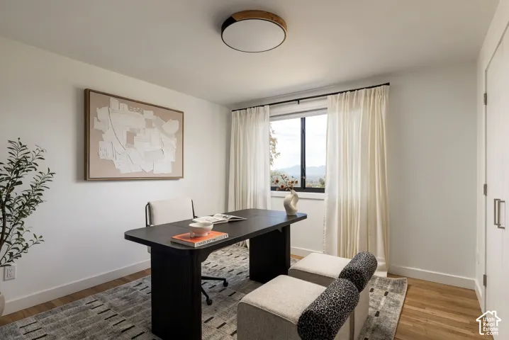 Neutral-toned interior featuring wood-finish flooring, a contemporary drum-style flush mount ceiling light, and a window with dark-framed casing