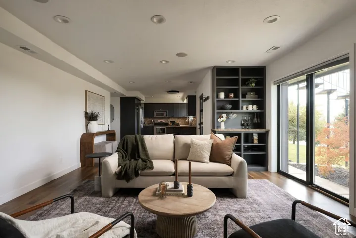 Open-concept interior featuring wood-finish flooring, recessed lighting, built-in dark cabinetry, and floor-to-ceiling glass sliding doors
