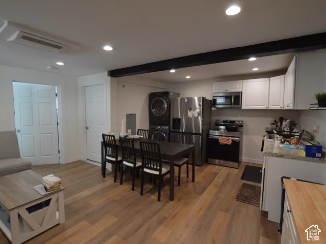 Apt 1. 775 SF. Kitchen area featuring white cabinetry, stone-finish countertops, stainless steel appliances and a structural ceiling beam