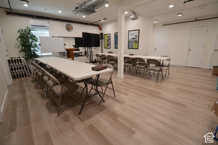 876 SF. Open-concept interior featuring light wood-finish flooring, recessed lighting, exposed industrial-style ceiling piping, and full-wall mirrors