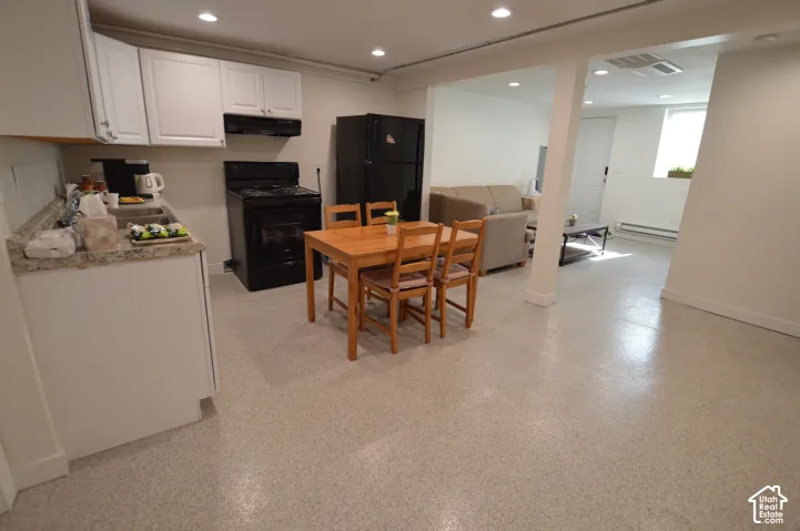 Apt 3. Kitchen featuring white shaker-style cabinetry, stone-finish countertops, recessed lighting, and epoxy flooring.