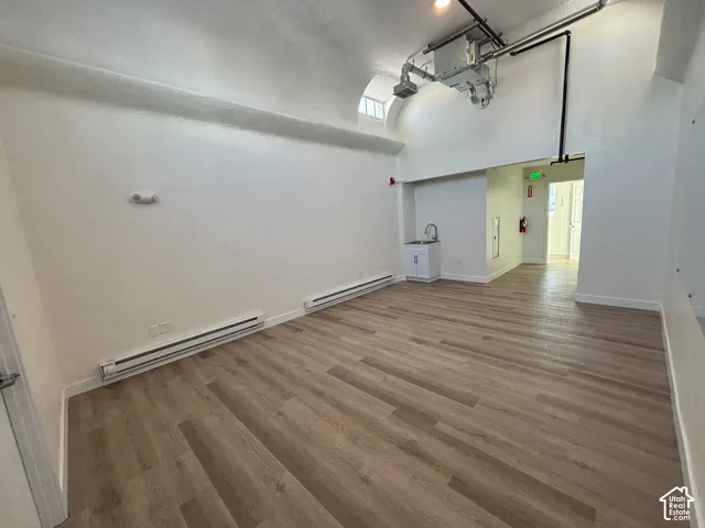 383 SF. High vaulted ceiling featuring exposed mechanical ductwork and wood-finish flooring throughout, complemented by a built-in wet bar with a stainless steel sink
