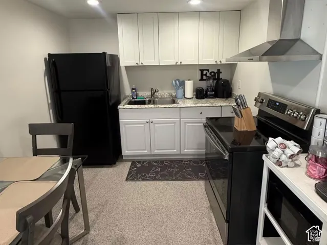 Apt 2. Kitchen featuring white cabinetry, stone-finish countertops, stainless steel range hood, recessed lighting, and resilient flooring.