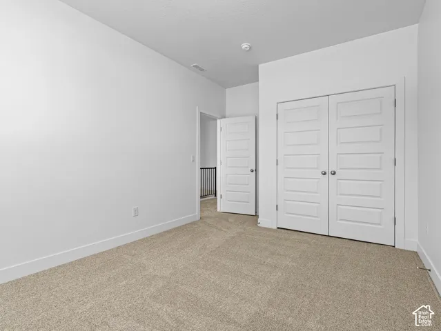 Neutral-toned carpeting, white walls, and interior doors featuring five-panel detailing