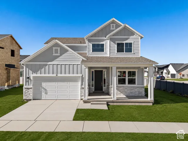Two-story exterior featuring light gray horizontal and vertical siding, stone veneer accents, a covered front porch, and a two-car garage